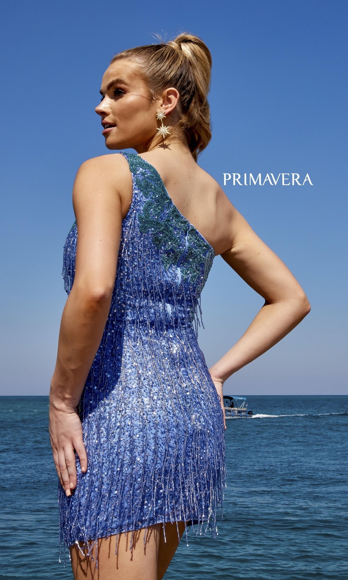 A woman wearing the Two-Tone Short Fringe Sequin Party Dress 4035 stands by the sea with a boat in the background. The word